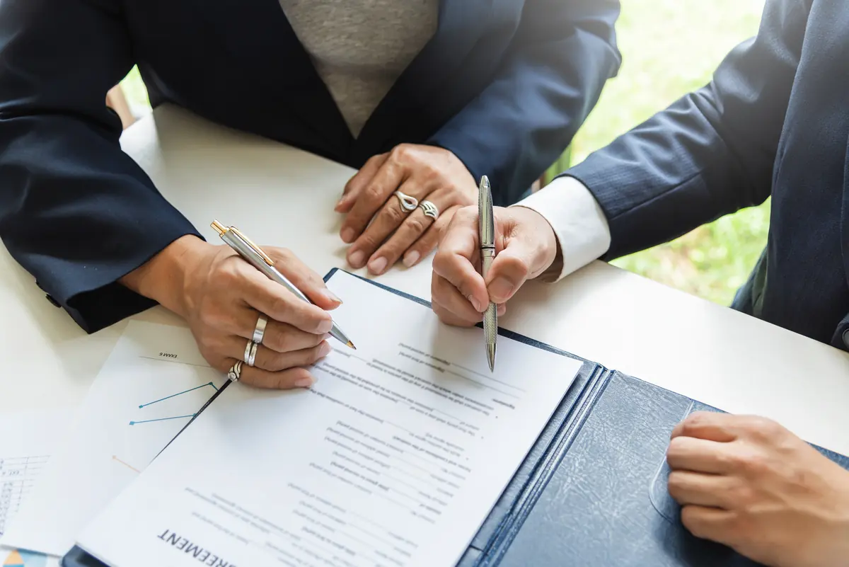 Two people signing a loan agreement at a desk