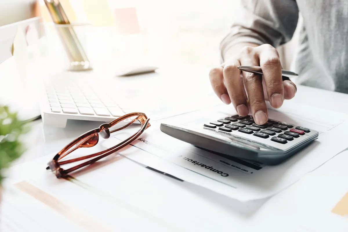 An accountant working on a calculator beside a financial report