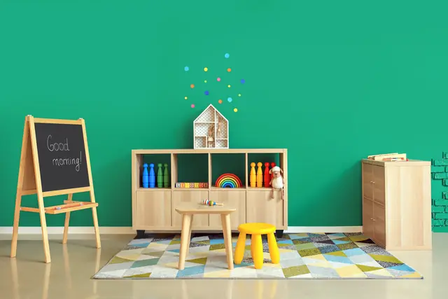 A preschool corner with an easel, a small table and chair, and low storage shelves